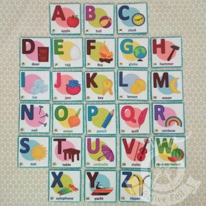 K&ouml;nnte beinhalten: Ein Satz von 26 Filz-Alphabet-Flashcards mit bunten Illustrationen und den entsprechenden W&ouml;rtern f&uuml;r jeden Buchstaben. Die Buchstaben sind in Gro&szlig;buchstaben und die W&ouml;rter in Kleinbuchstaben. Die Flashcards sind perfekt, um Kindern das Alphabet und grundlegende Vokabeln beizubringen.
