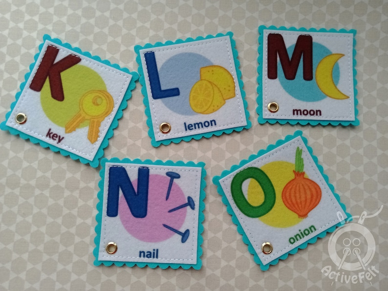K&ouml;nnte beinhalten: F&uuml;nf Filz-Alphabet-Karten mit einem Buchstaben, einem Bild und einem Wort. Die Buchstaben sind K, L, M, N und O. Die Bilder sind ein Schl&uuml;ssel, eine Zitrone, ein Mond, ein Nagel und eine Zwiebel.