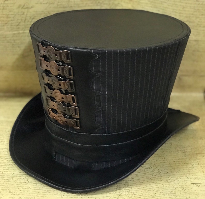 May include: A black top hat with a pinstripe pattern and a band of metal accents around the crown.