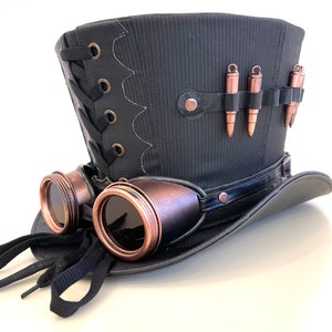 May include: A black top hat with a black leather band and a pair of copper-colored goggles attached to the side. The hat has a black and white striped pattern and a row of copper-colored bullets on the top.