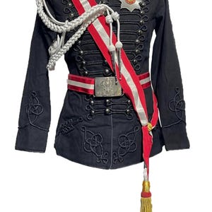 May include: Black military-style jacket with gold epaulets, decorative buttons, and intricate black embroidery. A red and white sash crosses the front, complemented by a silver and white cord and a gold tassel. The text "STEAMPUNK MASTERY" is visible.