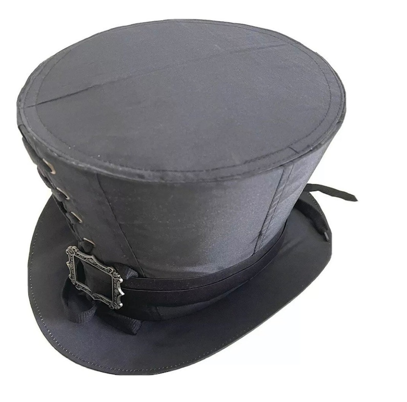 Op de afbeelding: Een zwarte hoge hoed met een brede rand en een decoratieve gesp. De hoed heeft een cilindrische kroon en een licht gebogen rand. Het heeft een lint en is waarschijnlijk gemaakt van vilt of een vergelijkbaar materiaal.
