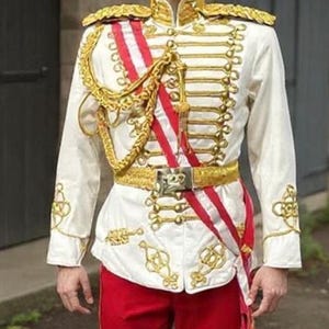 May include: A white military-style jacket with gold embellishments, paired with red pants. The jacket features gold epaulets, a row of gold buttons, and intricate gold embroidery. A red and white sash and gold belt complete the ensemble. The outfit is a historical costume.