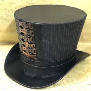 May include: A black top hat with a striped fabric band and a row of decorative metal accents. The hat has a wide brim.