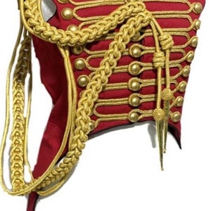 Op de afbeelding: Een rood en gouden vest in militaire stijl met gouden knopen en gevlochten trim. Het vest heeft een hoge kraag en een lange staart.
