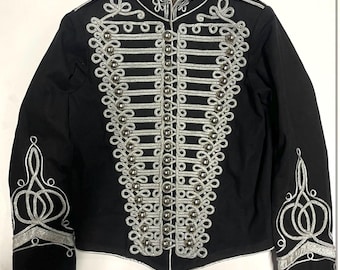 May include: Black military-style jacket with silver-colored embellishments. The jacket features ornate silver embroidery and decorative buttons down the front. The sleeves have detailed silver designs. The jacket has a high collar.