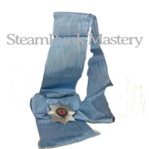 May include: A light blue sash with a decorative silver and red emblem. The sash has a fringed edge and the text "SteamPunk Mastery" in the upper left corner. The emblem features a red cross.