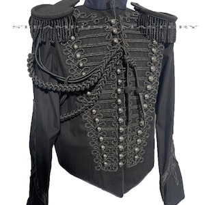 May include: A black military-style jacket with a high collar, intricate gold braid detailing, and silver buttons. The jacket has epaulets with black fringe and a braided rope accent.