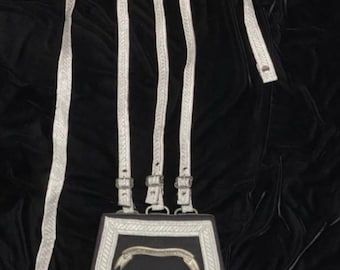 May include: A black leather pouch with a silver skull and crossbones design. The pouch is attached to a set of white straps with silver buckles. The text "Steam Punk Mastery" is visible in the image.