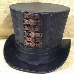 May include: A black top hat with a striped pattern and a row of decorative metal buckles. The hat has a wide brim and a tall crown.