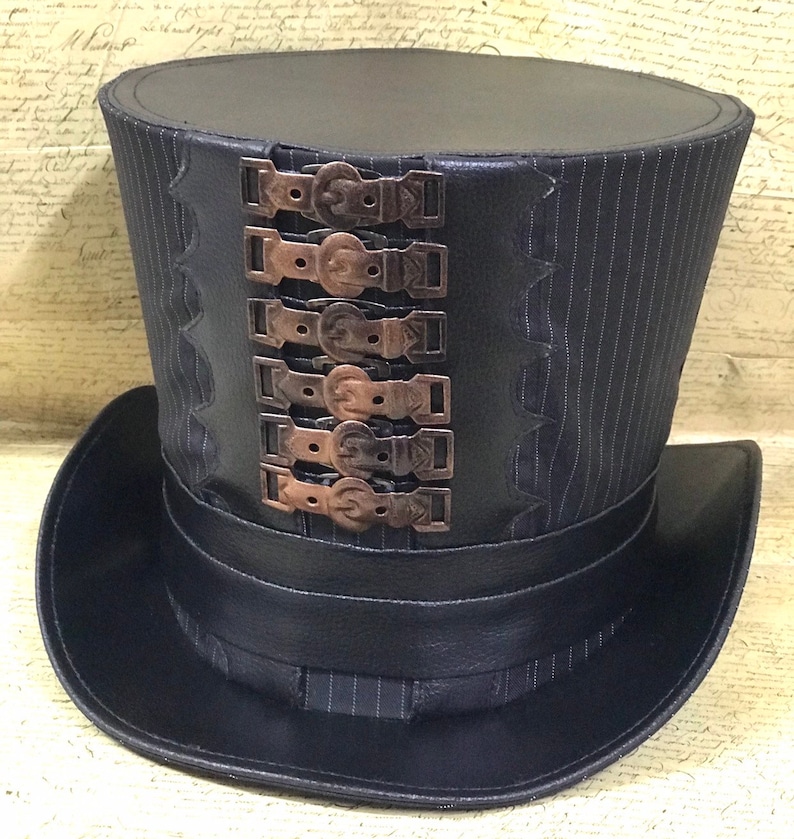 May include: A black top hat with a striped pattern and a row of decorative metal buckles. The hat has a wide brim and a tall crown.