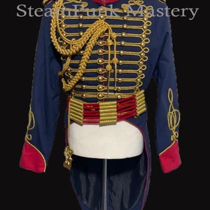 May include: A navy blue jacket with gold and red trim. The jacket has a high collar and a long tail. It features a gold braid design and gold buttons. The jacket is on a mannequin.
