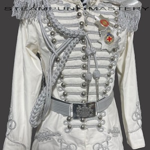 May include: A white military-style jacket with silver trim and buttons. The jacket has a high collar and a belt with a silver buckle. The jacket is decorated with silver braid and tassels. The jacket has a silver badge on the left side of the chest.