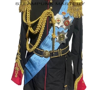 Può includere: Un'uniforme militare nera con rifiniture dorate e una fascia blu. L'uniforme presenta una varietà di medaglie e decorazioni, tra cui una corona e una croce.