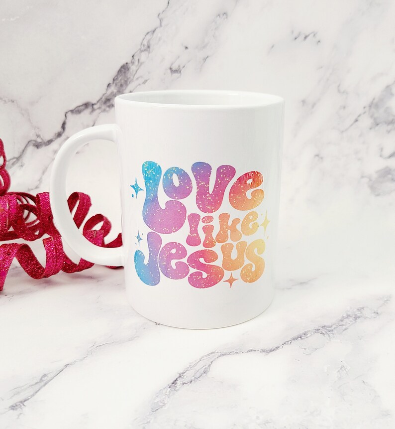 May include: White ceramic coffee mug with a rainbow gradient design that says "Love like Jesus" in a retro font.