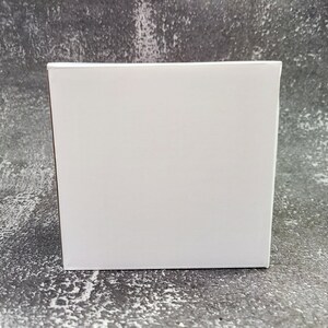 May include: A plain white cardboard box with a smooth surface.