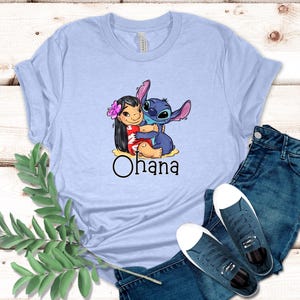 May include: Light blue t-shirt with a graphic of Stitch and Lilo hugging. The text "Ohana" is printed below the image.