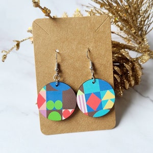 May include: A pair of round wooden earrings with a geometric pattern in shades of blue, green, pink, red, and yellow. The earrings are hanging from silver hooks.