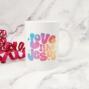 May include: White ceramic coffee mug with a rainbow glitter design that says "Love like Jesus".