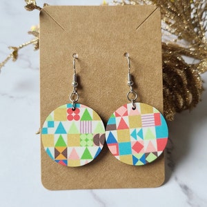 May include: A pair of colourful geometric pattern earrings. The earrings are round and made of wood with silver hooks.