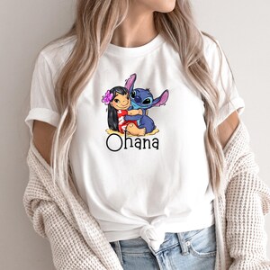 May include: White t-shirt with a cartoon image of Stitch hugging Lilo. The shirt has the word "Ohana" printed below the image.