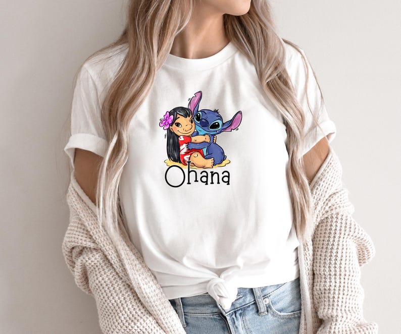 May include: White t-shirt with a cartoon image of Stitch hugging Lilo. The shirt has the word "Ohana" printed below the image.
