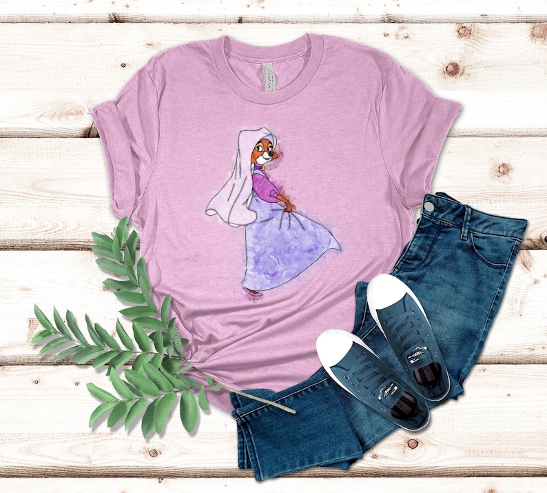 Op de afbeelding: Een roze T-shirt met een aquarel-illustratie van een cartoonvos die een paarse jurk en een witte sluier draagt. De vos kijkt naar rechts en heeft een roze neus en bruine ogen.