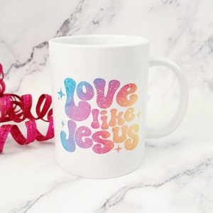 May include: White ceramic coffee mug with a rainbow gradient design that says "Love like Jesus" in a retro font.