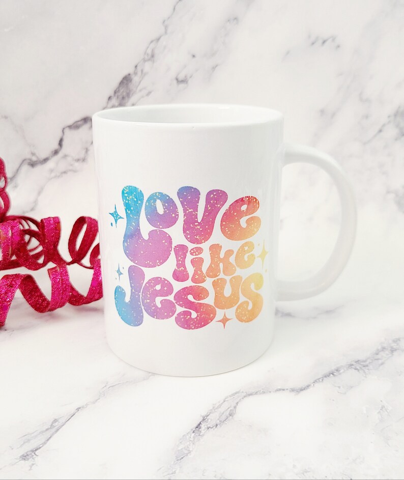 May include: White ceramic coffee mug with a rainbow gradient design that says "Love like Jesus" in a retro font.