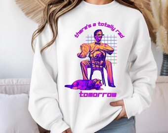 May include: White sweatshirt with a retro graphic. It features a man in sunglasses, a dog, and the text "there's a totally rad tomorrow" in purple and pink. The design has a grid background.