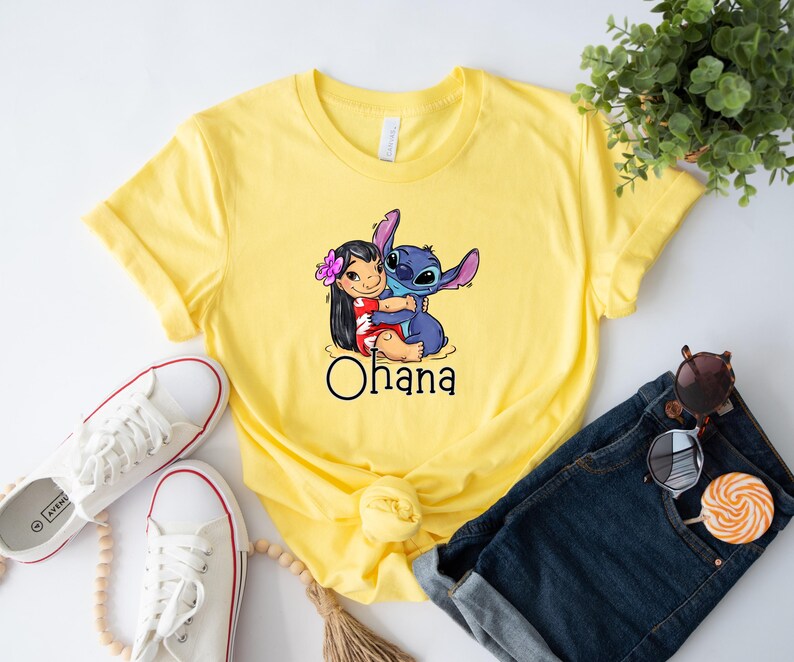May include: Yellow t-shirt with a graphic of Stitch and Lilo hugging. The text "Ohana" is printed below the image.