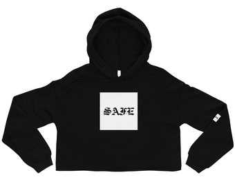 Puede incluir: Sudadera con capucha negra recortada con un cuadrado blanco en la parte delantera que dice "SAFE" en una fuente gótica.