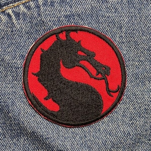May include: A red and black embroidered patch featuring a dragon head, a popular symbol in video games and fantasy.