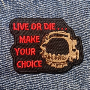 Könnte beinhalten: Ein gestickter Aufnäher mit einem Totenkopf- und Knochen-Motiv in Schwarz und Rot. Der Text auf dem Aufnäher lautet "Live or Die... Make Your Choice".