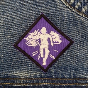 May include: Purple diamond-shaped patch with a white silhouette of a person running with their arms outstretched. The person is running through a field of white lines.