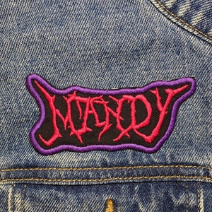 May include: A denim jacket with a purple and pink embroidered patch that says "NOFX" on it.