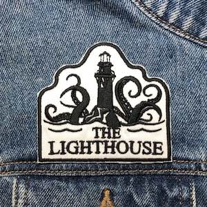 Könnte beinhalten: Schwarz-weiß gestickter Patch eines Leuchtturms, um den sich ein Tintenfisch windet. Der Text "The Lighthouse" befindet sich unter dem Bild.