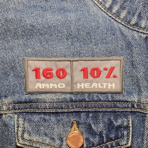 May include: A gray denim jacket with a patch that reads "160 AMMO 10% HEALTH".