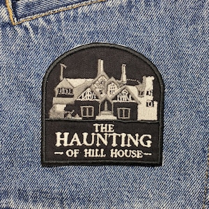 Könnte beinhalten: Schwarz-weiß gestickter Aufnäher mit einer Silhouette eines Hauses und dem Text "THE HAUNTING - OF HILL HOUSE -"