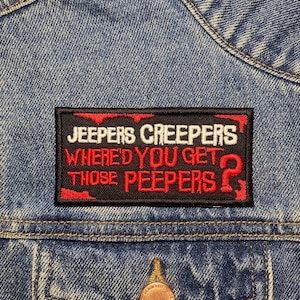 May include: A black and red embroidered patch with the text "Jeepers Creepers Where'd You Get Those Peepers?" on a blue denim jacket.