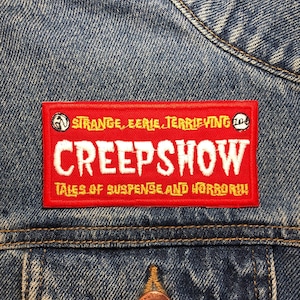 Op de afbeelding: Rode en gele geborduurde patch op een spijkerjack. De patch zegt "Creepshow Tales of Suspense and Horror!" met een klein logo boven de tekst.