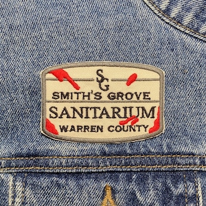 May include: An embroidered patch in beige and red with the text "Smith's Grove Sanitarium Warren County" and the letters "S&G" above the text.
