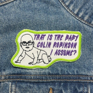 Może przedstawiać: Naszywka haftowana na zielono i biało z kreskówkowym rysunkiem dziecka w okularach. Tekst na naszywce brzmi "That is the baby Colin Robinson I assume?"