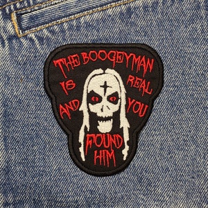 May include: A black and red embroidered patch with the text "The Boogeyman is Real and You Found Him" on a blue denim jacket.
