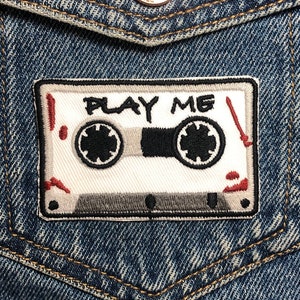 Parche bordado con la frase "Play Me Cassette Tape" (Reproduce mi casete). Parches inspirados en películas de terror. Reverso termoadhesivo.