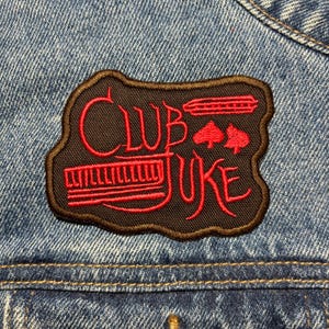 May include: A white ceramic mug with a black handle and the text "But First, Coffee" in a handwritten style. The mug is on a white surface. The mug is approximately 10 cm tall.