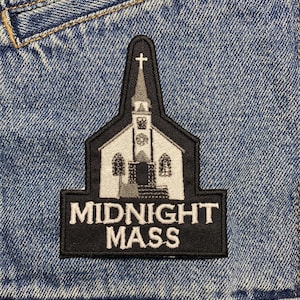 May include: Black and white embroidered patch of a church with a cross on top and the text "MIDNIGHT MASS" underneath.