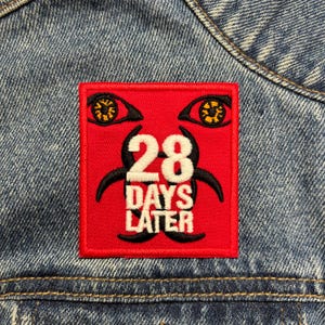以下が含まれることがあります： バイオハザードシンボル、数字の28、そして「Days Later」というテキストが書かれた赤い刺繍パッチ。パッチの上には黄色い目が2つある。
