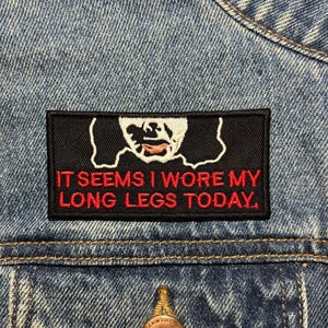 Op de afbeelding: Een zwart-witte strijkpatch met rode tekst die "Het lijkt erop dat ik mijn lange benen vandaag heb gedragen." zegt.