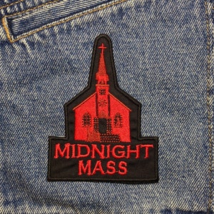 Op de afbeelding: Rode en zwarte geborduurde patch met een kerkgebouw en de tekst "MIDNIGHT MASS".